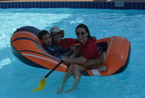 Two swim instructors with a little boy in an inflatable boat