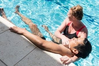A woman holding a man up along the edge of a pool while practising rescue
