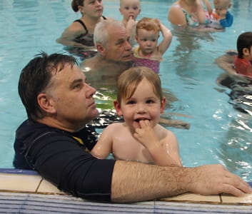 toddler boy in the pool with his dad during an infant aquatics class