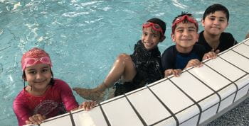 Four Islamic students in the pool smiling at the camera