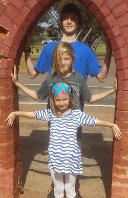 Jewel with her two brothers standing under an arch