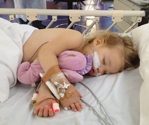 Jewel laying in a hospital bed with tubes attached to her