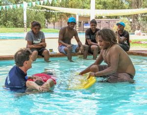 Jigalong youth with trainer Cameron Eglington demonstrating rescue with a spine board in the pool