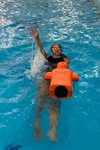girl practising a pool rescue manikin tow