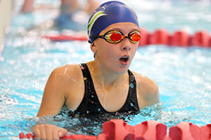 A girl in the pool wearing goggles and a swim cap