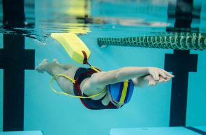 A girl swimming underwater while towing a rescue tube