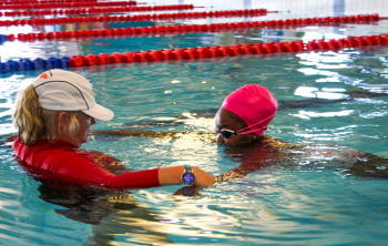 A swim instructor in the water with their student
