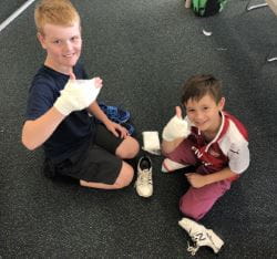 two boys practising bandaging and giving a thumbs up