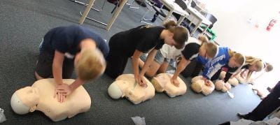 children in a row practising CPR