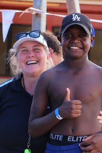 A Royal Life Saving staff member with an Aboriginal boy by the pool
