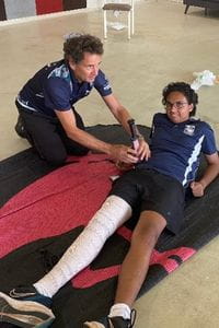 First aid trainer demonstrating bandaging a leg on student