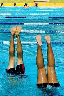 two pairs of legs sticking vertically out of a pool