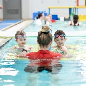 Two children in the pool with their swim instructor