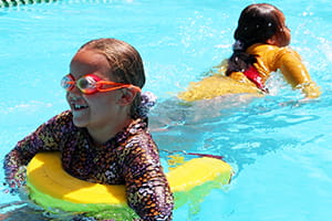 Two children in the pool using a rescue tube