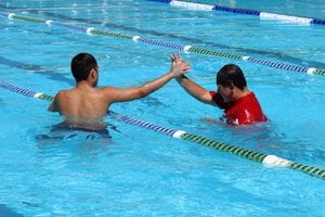 Two kids in pool giving high five