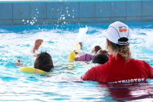 An instructor with children swimming in the pool