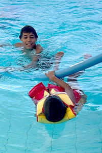 Two kids practising rescue skills in the pool