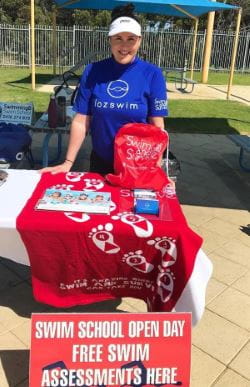 Lozswim staff member at a table with Swim and Survive info and a sign about Free Swim Assessments