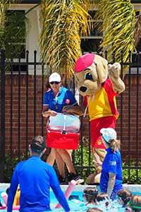 Swim instructors with a Walter the Watch Dog mascot by the swimming pool
