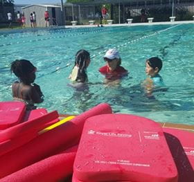 Swimming instructor in the water with three girls doing a swimming lesson
