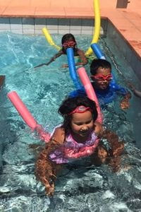 Aboriginal children in the pool with pool noodles
