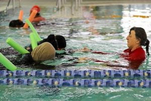 Two multicultural women wearing headscarves during a swimming lesson with their instructor