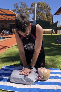 Newman SHS staff member practising CPR on a manikin