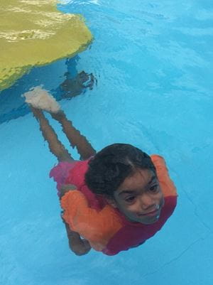 young aboriginal girl swimming up from bottom of swimming pool