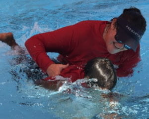 A swim instructor helping an Aboriginal children learn to swim in a pool