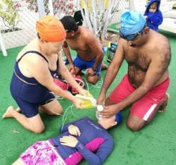 male and female lifeguards practising oxygen resuscitation techniques by the poolside