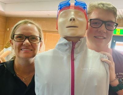 Swim school coordinator Tracye Sykes with an AUSTSWIM course candidate standing with a resuscitation Anne doll