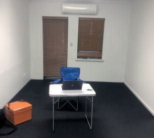 An empty office with just a plastic table and camping chair