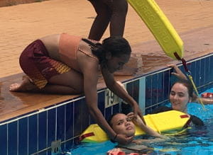 A group of girls practising spineboard rescue at the edge of the pool