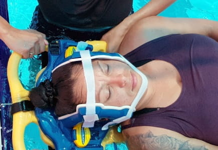 close up of woman strapped to spinal board floating in swimming pool