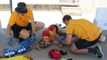 Two lifeguards attending to a person passed out on the ground