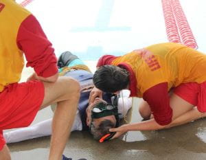 A lifeguard checking a man who has just been pulled from the water