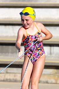 A girl wearing a yellow swim cap pulling a rescue rope