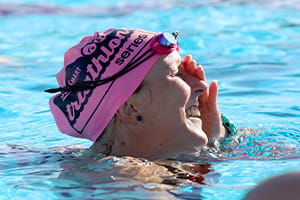 A woman wearing a pink swim cap in the water