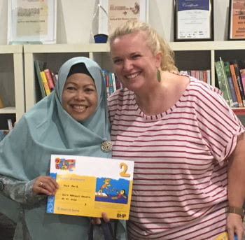 A woman wearing a head scarf receiving her swimming certificate from her swim instructor