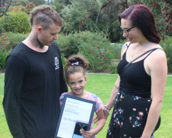 Kirk Ugle with Ruby-Maree and her mum Tahni Fowler, Ruby is holding her Royal Life Saving Bravery Award