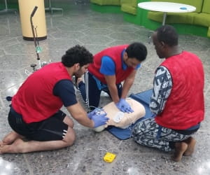 three saudi lifeguards practising CPR on manikin