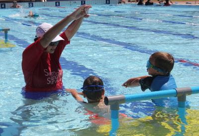 A swim instructor with two children in the water at Gingin