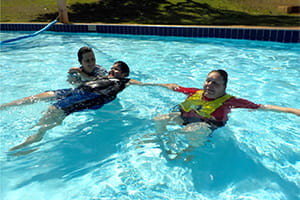 A swim instructor in the pool with two students