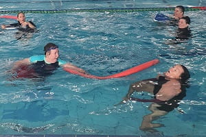 aquatic trainer practises a reach rescue with a pool noodle
