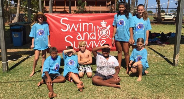 A group of aboriginal children in front of the red Swim and Survive banner at the Spirit Carnival