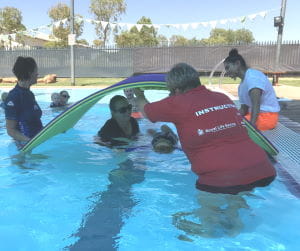 Instructor Adele Caporn helping a mum and toddler through a mat tunnel in the pool at Fitzroy Crossing