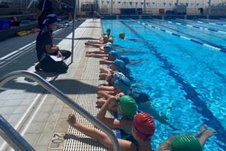 St Hilda's girls lined up along the side of the pool facing trainer Cameron Eglington