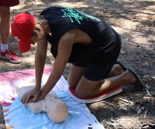 image of a Scouts member practising CPR on a manikin by the river