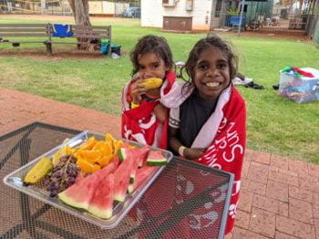 Two Aboriginal children eating fruit while wrapped in towels