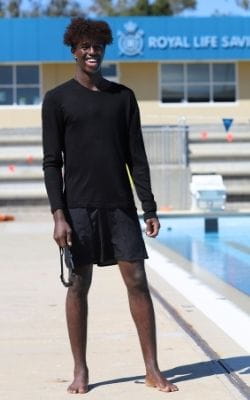 man in swimwear standing next to outdoor pool